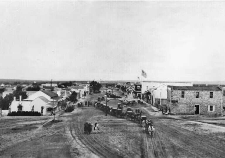 Horse and carriage parade on Main Street in Fredericksburg, Texas, in 1896, with the limestone Maier Building at right