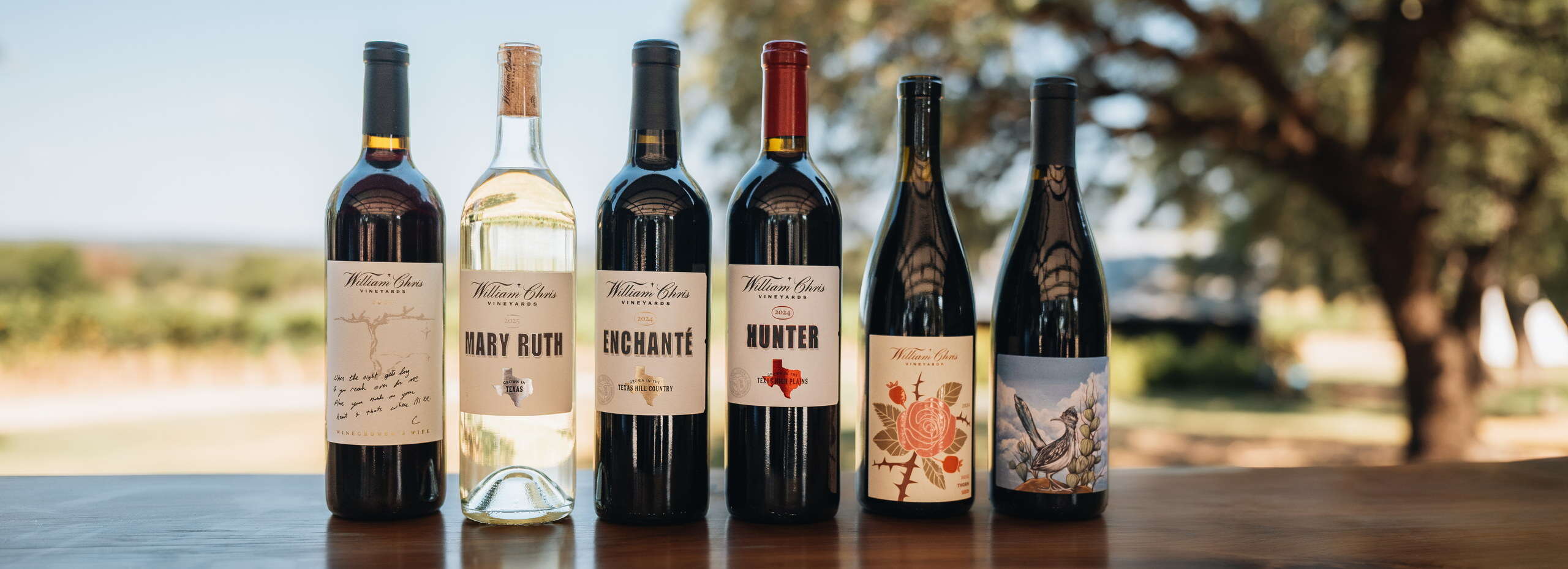 Mary Ruth, Enchanté, Hunter and other William Chris wines on a table under a live oak
